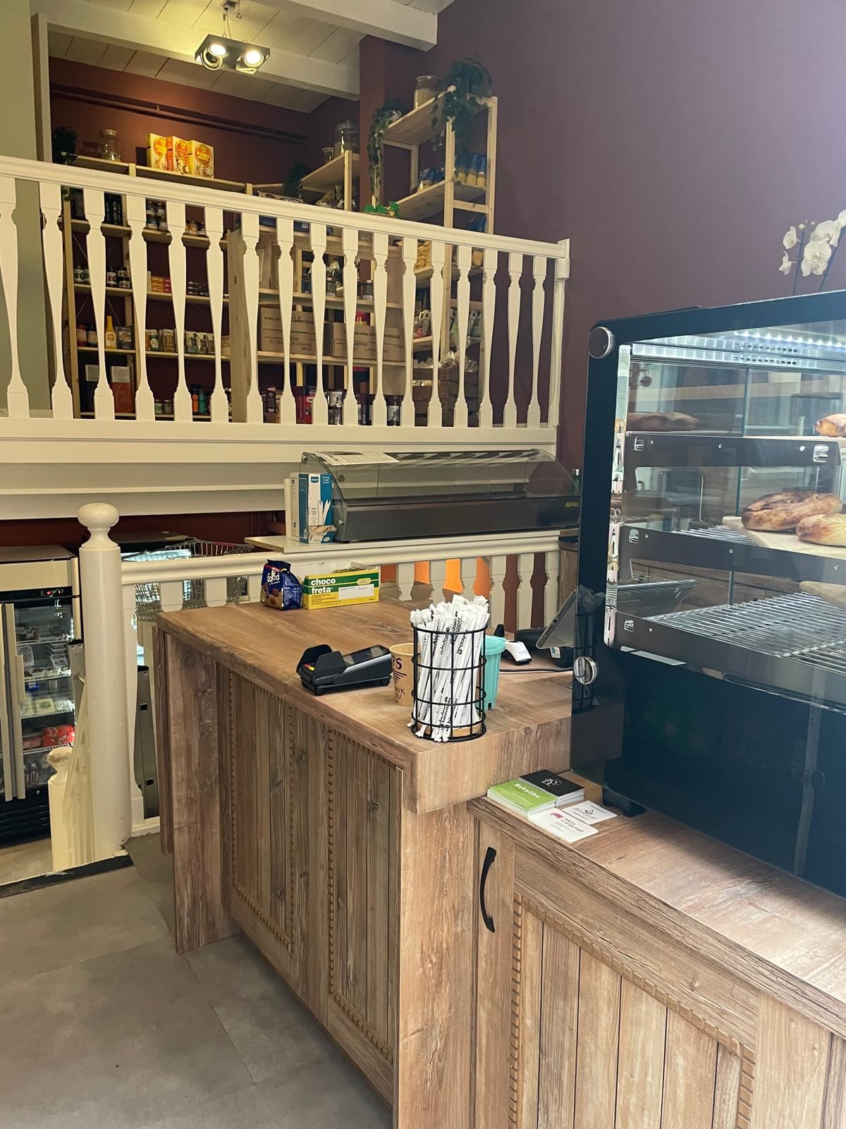 Counter with a display case of Greek pies and pastries, and shelves of Greek products behind it, inside Bakaliko Amsterdam