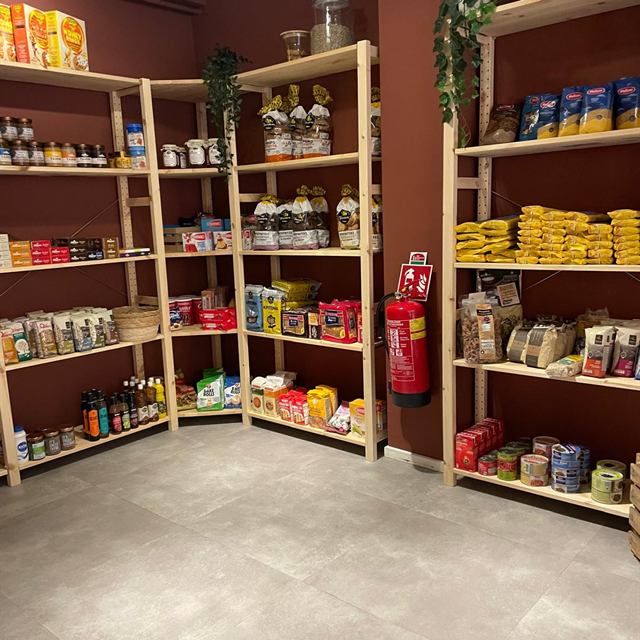 Houten schappen met Griekse pasta, peulvruchten, blikken en potten op de bovenverdieping