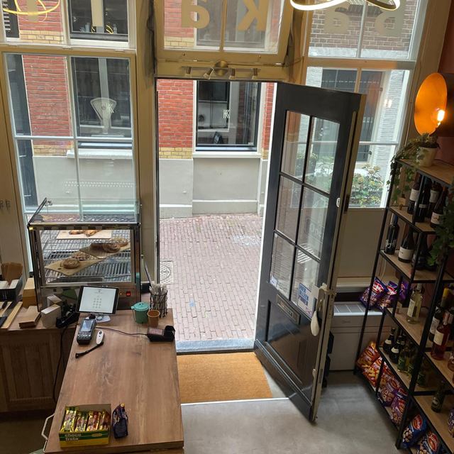 Kijkje van bovenaf op de ingang met links de vitrine met gebak en rechts de wijnschappen