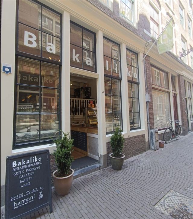 Winkelpui van Bakaliko in Amsterdam met het bord van de Griekse deli en koffie op de stoep