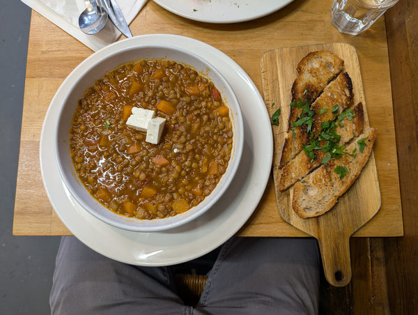Bowl of Greek lentil soup with a cube of feta and toasted bread