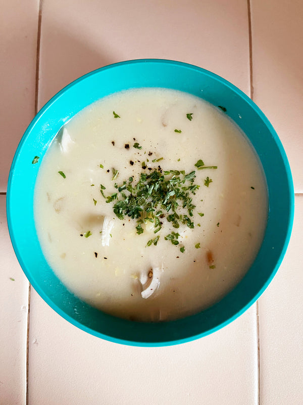 Bowl of avgolemono soup with chicken and chopped herbs