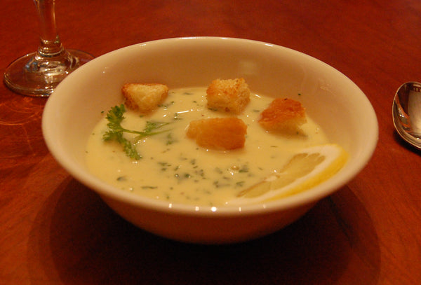 Kom avgolemono-soep met croutons en een schijfje citroen