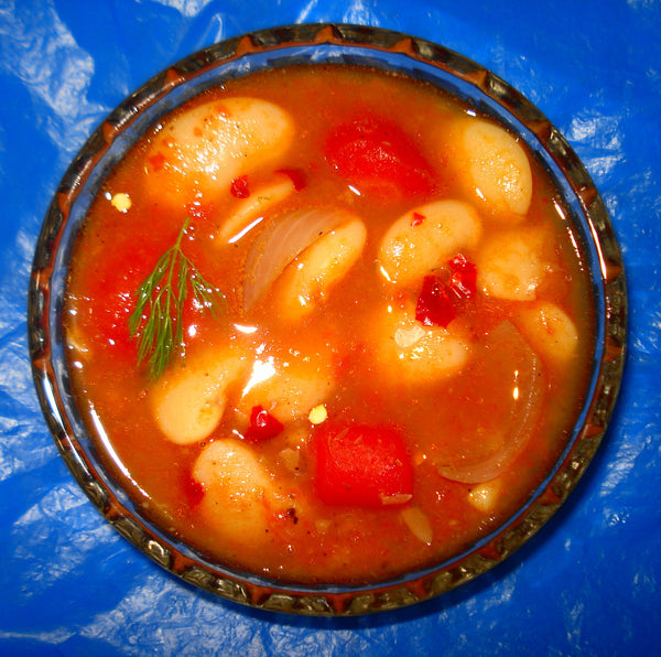 Bowl of white bean soup in tomato broth with onion and herbs