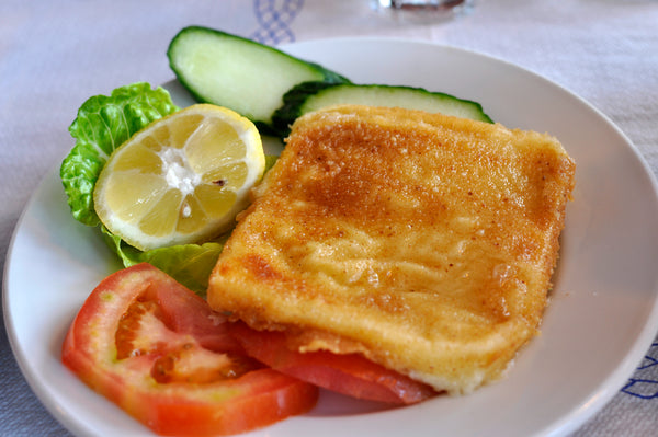 Fried saganaki cheese with lemon, tomato and cucumber