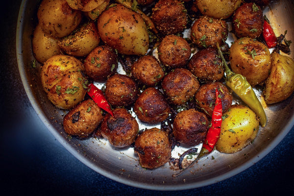Fried meatballs with baby potatoes and chilli peppers in a pan