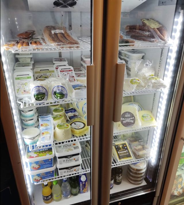 Koelkast met Griekse kazen zoals feta, halloumi, graviera en manouri, en Griekse worstjes bij Bakaliko Amsterdam