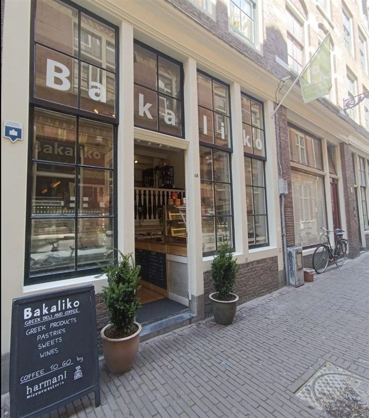 Voorgevel van Bakaliko Griekse deli en koffie aan de Sint Nicolaasstraat 68 in Amsterdam, met het bord op de stoep